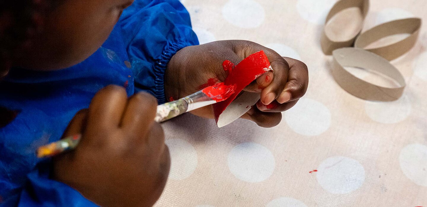 Sicht auf ein Kind von oben, das eine Blume aus Karton bastelt